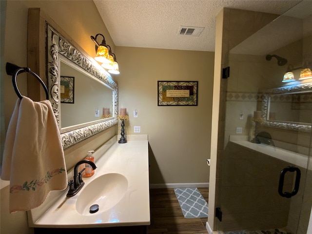 bathroom featuring vanity, a shower with door, a textured ceiling, and hardwood / wood-style floors