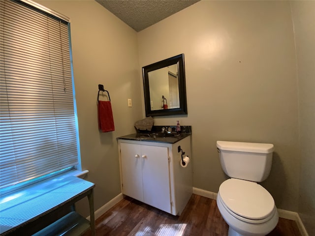 bathroom featuring toilet, wood-type flooring, vanity, and a textured ceiling