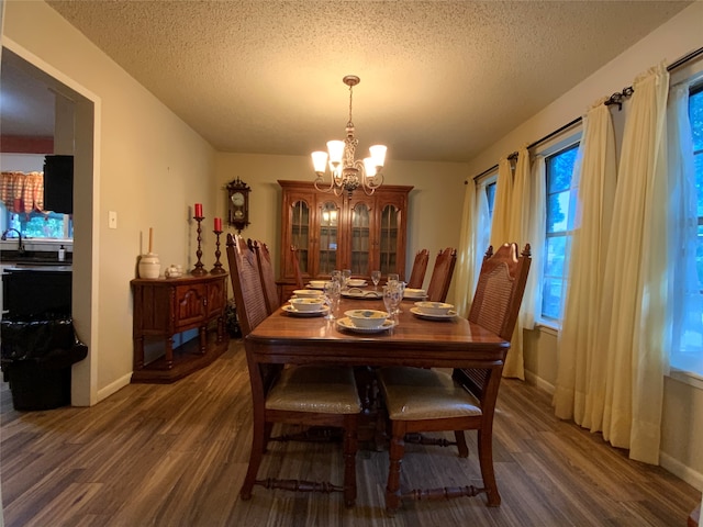 dining room featuring a chandelier, dark wood-type flooring, and a textured ceiling