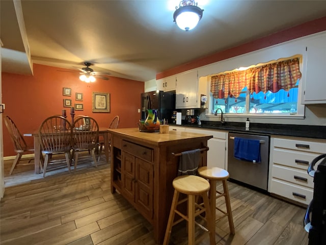 kitchen featuring white cabinets, dark wood-type flooring, black fridge, and stainless steel dishwasher