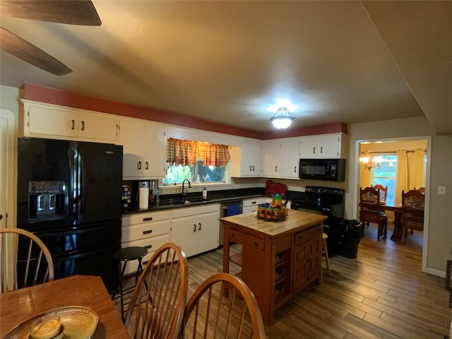 kitchen featuring hardwood / wood-style floors, a wealth of natural light, sink, white cabinetry, and black appliances