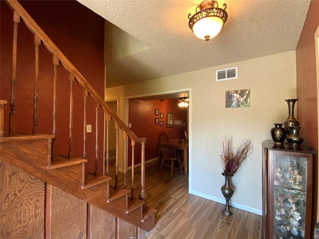 stairs featuring hardwood / wood-style flooring and a textured ceiling