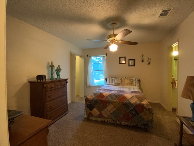 bedroom with ceiling fan, carpet floors, and a textured ceiling