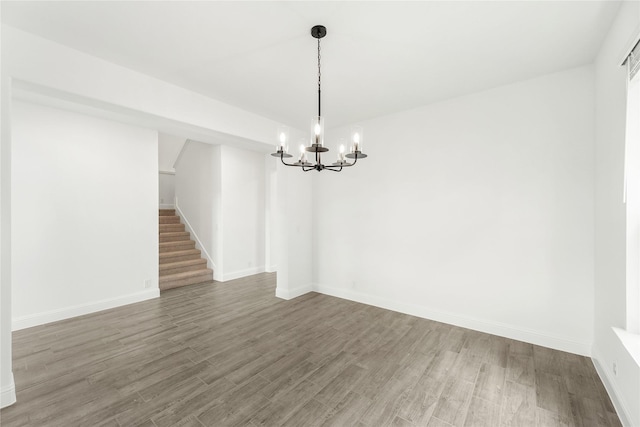 unfurnished room featuring an inviting chandelier and hardwood / wood-style floors