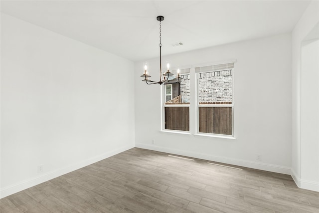 unfurnished dining area with a chandelier and light hardwood / wood-style flooring