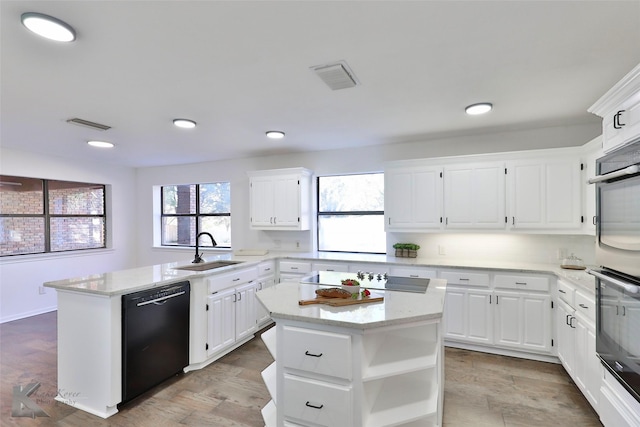 kitchen featuring sink, light stone counters, black appliances, a center island, and white cabinets