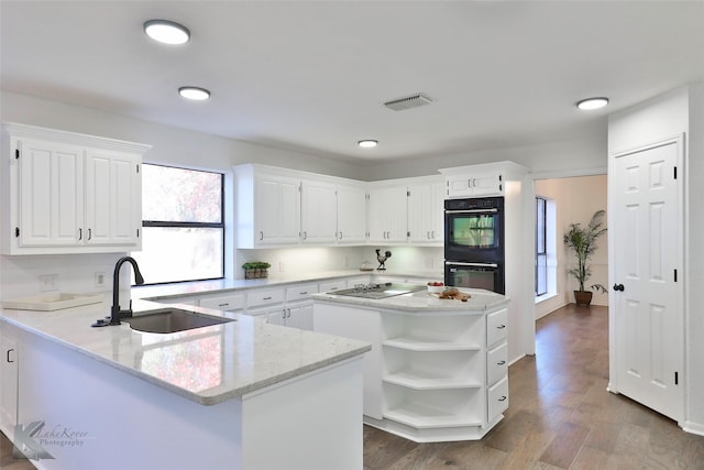 kitchen featuring sink, black appliances, light stone countertops, white cabinets, and kitchen peninsula