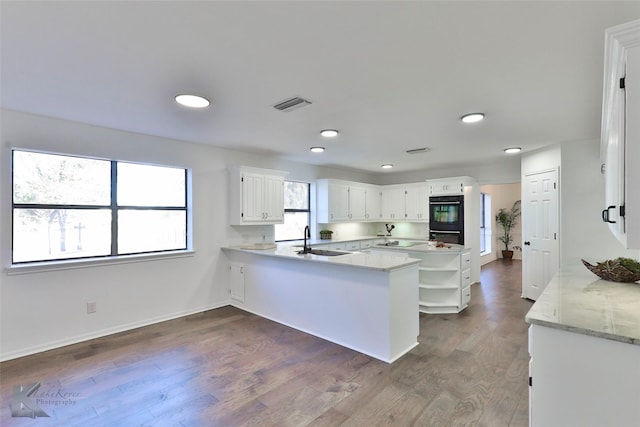 kitchen featuring dark hardwood / wood-style floors, white cabinetry, sink, black double oven, and kitchen peninsula