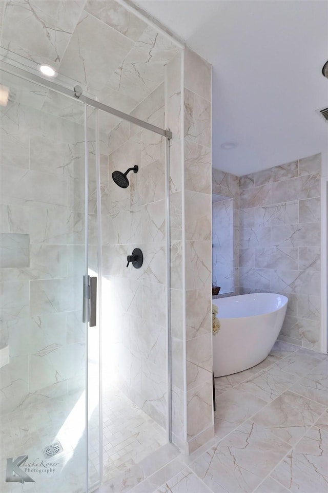 bathroom featuring shower with separate bathtub and tile walls