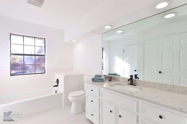 bathroom with vanity, plenty of natural light, a tub to relax in, and toilet