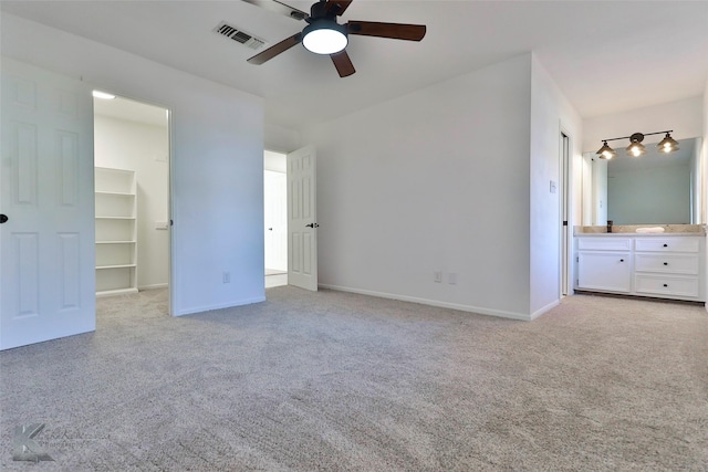 unfurnished bedroom with ceiling fan, a walk in closet, and light carpet