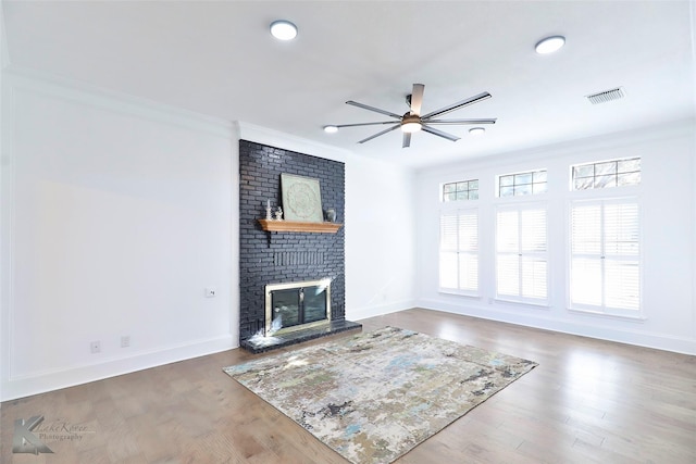 unfurnished living room featuring crown molding, hardwood / wood-style flooring, a fireplace, and ceiling fan