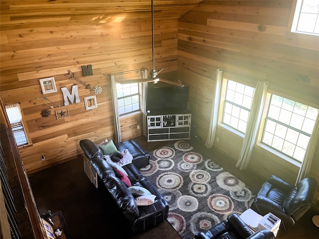 unfurnished living room with wooden walls, ceiling fan, and plenty of natural light