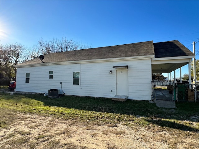 back of house featuring central air condition unit and a lawn