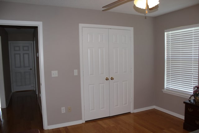 unfurnished bedroom with dark hardwood / wood-style floors, ceiling fan, and a closet