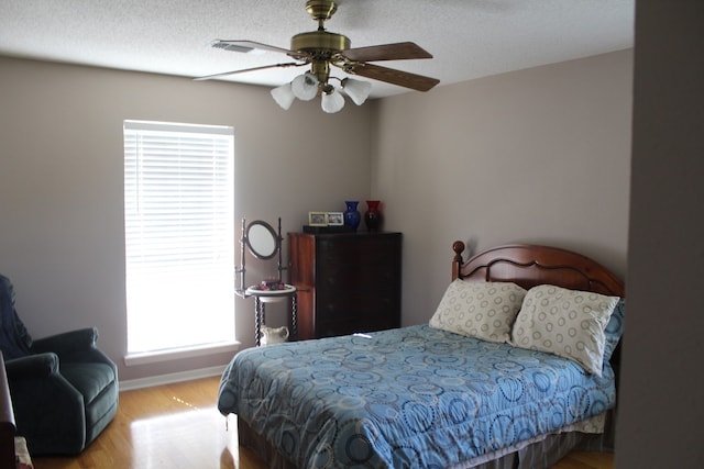 bedroom with a textured ceiling, ceiling fan, and wood-type flooring