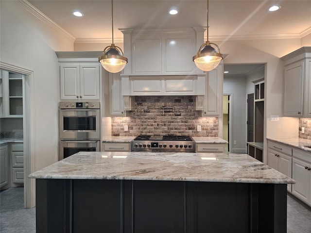 kitchen with light stone countertops, a kitchen island, appliances with stainless steel finishes, and decorative light fixtures