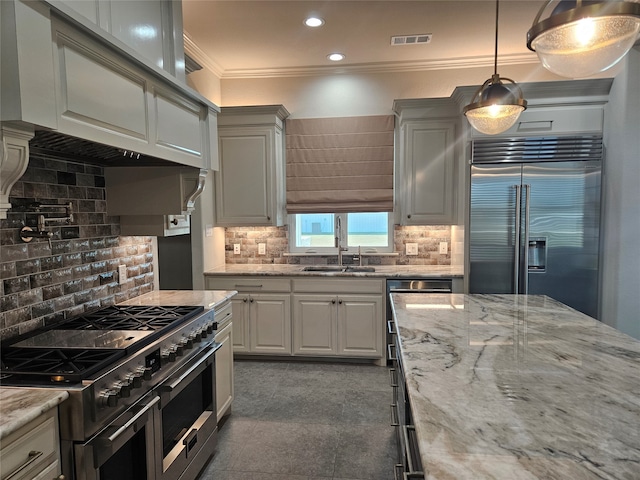 kitchen featuring backsplash, crown molding, premium appliances, and decorative light fixtures