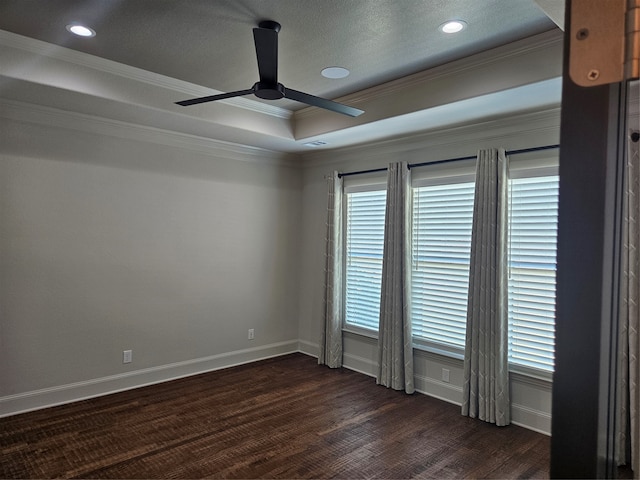 empty room with dark wood-type flooring, a raised ceiling, a textured ceiling, crown molding, and ceiling fan