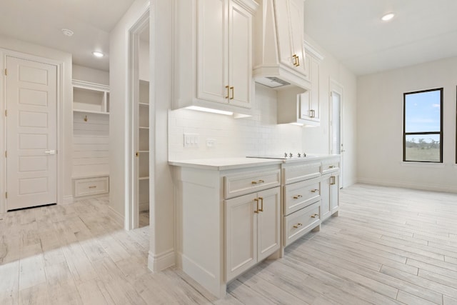 kitchen with light hardwood / wood-style flooring, tasteful backsplash, and white cabinets