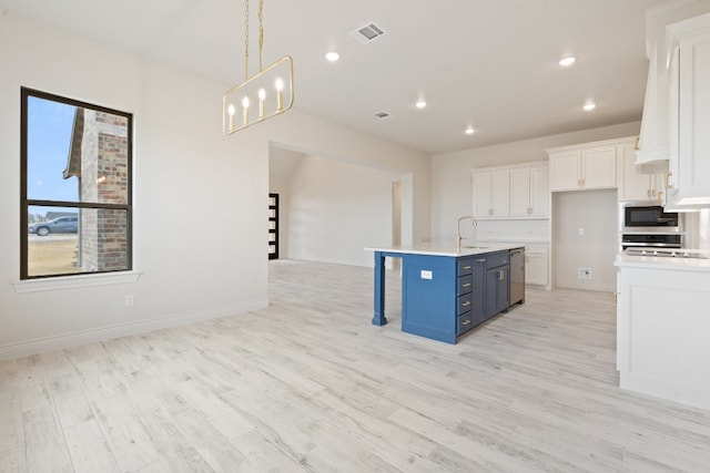 kitchen with blue cabinetry, white cabinetry, an island with sink, and light wood-type flooring