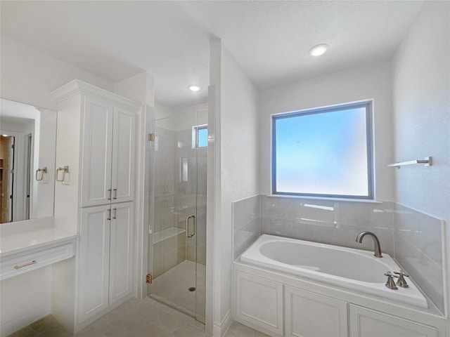 bathroom with a textured ceiling, tile flooring, and separate shower and tub