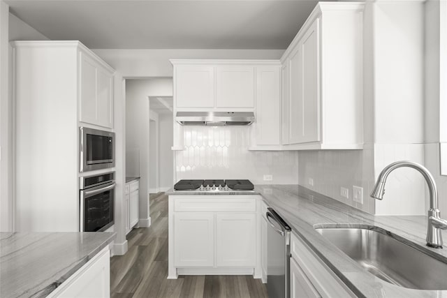 kitchen featuring sink, appliances with stainless steel finishes, white cabinetry, light stone counters, and tasteful backsplash