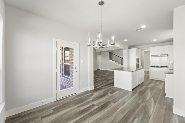 kitchen with white cabinetry, hanging light fixtures, dark hardwood / wood-style floors, a kitchen island, and backsplash