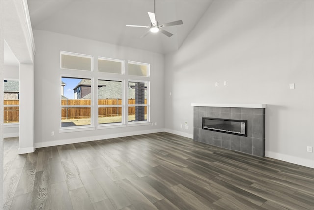 unfurnished living room featuring a tile fireplace, high vaulted ceiling, ceiling fan, and dark hardwood / wood-style flooring