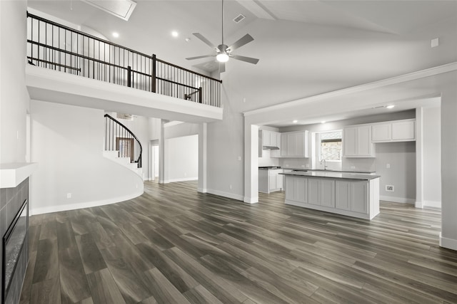 unfurnished living room with ceiling fan, dark hardwood / wood-style floors, high vaulted ceiling, and a tile fireplace