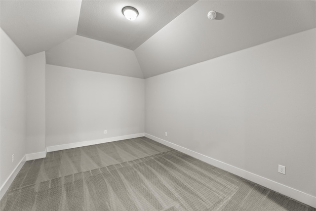 spare room featuring vaulted ceiling and carpet flooring