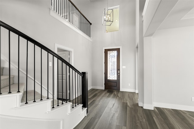 entrance foyer featuring dark hardwood / wood-style flooring, an inviting chandelier, and a high ceiling