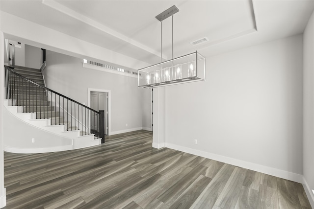 unfurnished dining area featuring dark wood-type flooring and a tray ceiling