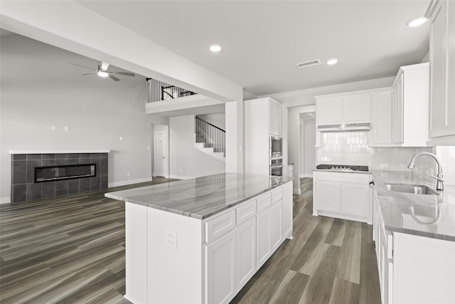 kitchen with white cabinetry, a center island, sink, and stone countertops