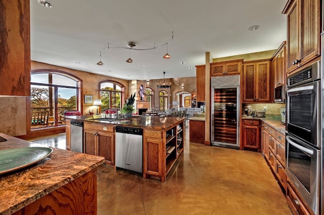 kitchen with dark stone counters, sink, a kitchen island, and built in appliances