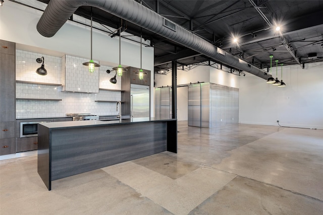 kitchen with sink, a towering ceiling, built in fridge, and a barn door