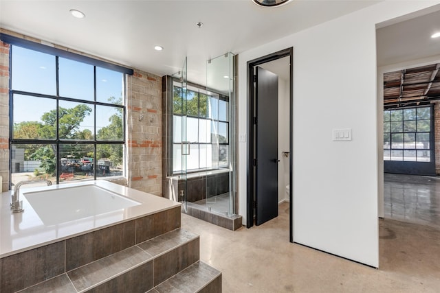 bathroom featuring concrete flooring and a relaxing tiled tub