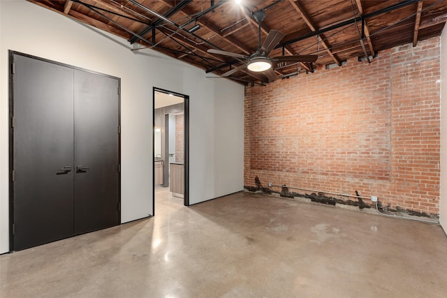 interior space featuring ceiling fan and brick wall