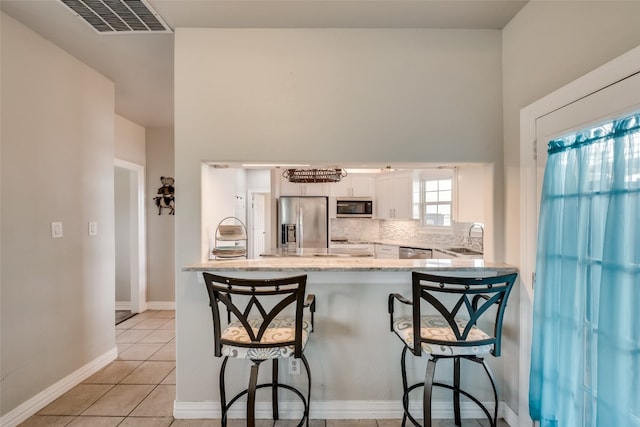 kitchen with white cabinets, appliances with stainless steel finishes, sink, and a breakfast bar area