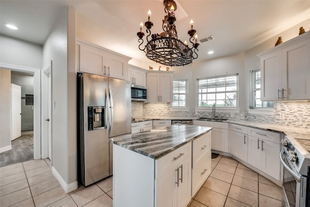 kitchen with stainless steel appliances, white cabinetry, and a center island