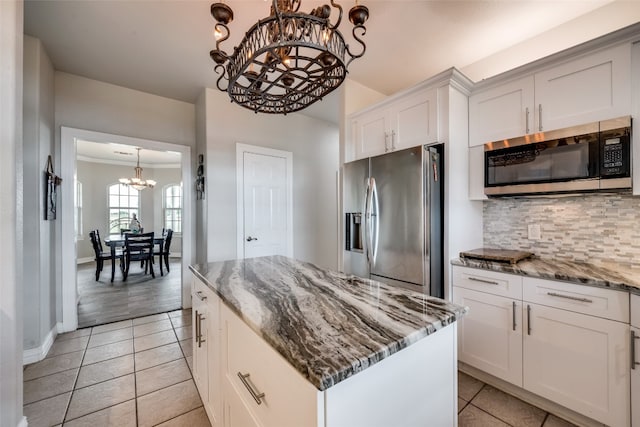 kitchen featuring appliances with stainless steel finishes, stone countertops, white cabinetry, and a center island