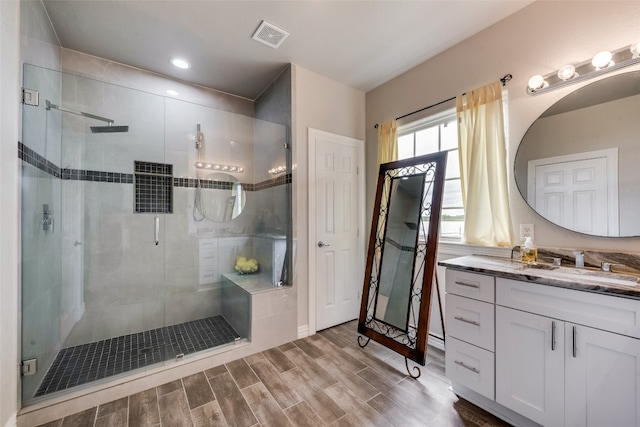 bathroom featuring wood-type flooring, a shower with shower door, and vanity