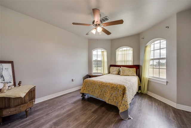 bedroom featuring ceiling fan, dark hardwood / wood-style floors, and multiple windows