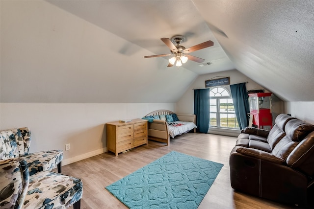 bedroom featuring ceiling fan, a textured ceiling, light wood-type flooring, and vaulted ceiling