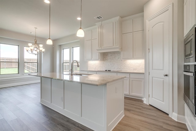 kitchen featuring white cabinetry, light hardwood / wood-style flooring, a kitchen island with sink, and sink