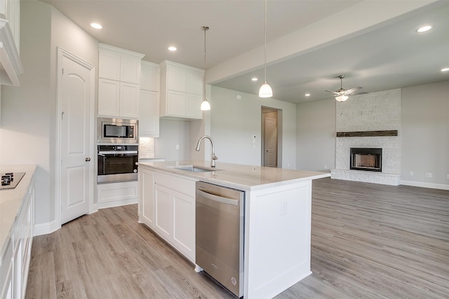 kitchen featuring a fireplace, white cabinets, sink, appliances with stainless steel finishes, and light hardwood / wood-style flooring