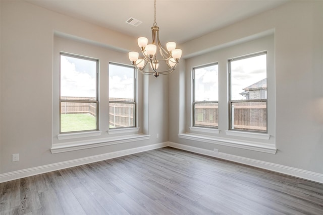 unfurnished room with a notable chandelier and hardwood / wood-style floors