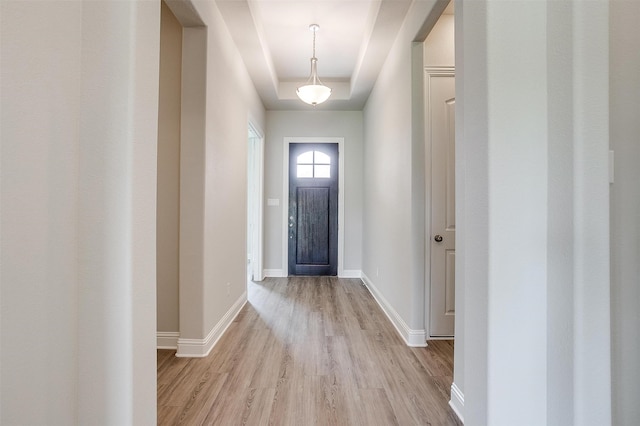 doorway featuring light hardwood / wood-style flooring and a raised ceiling