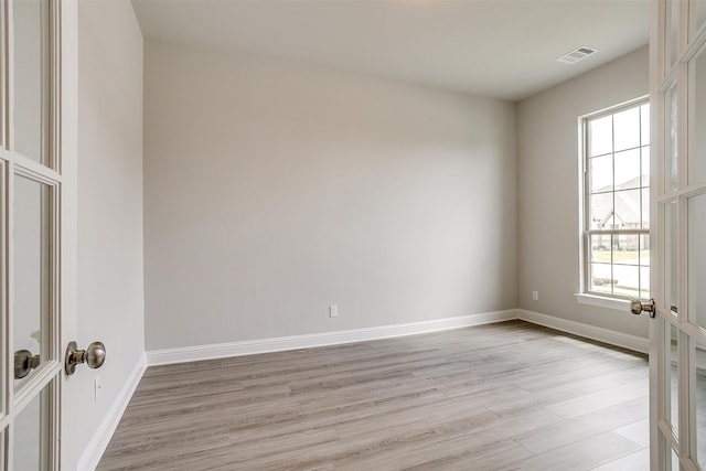 spare room with light hardwood / wood-style floors and french doors