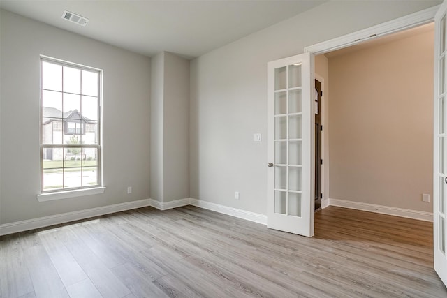 empty room with light hardwood / wood-style flooring and french doors